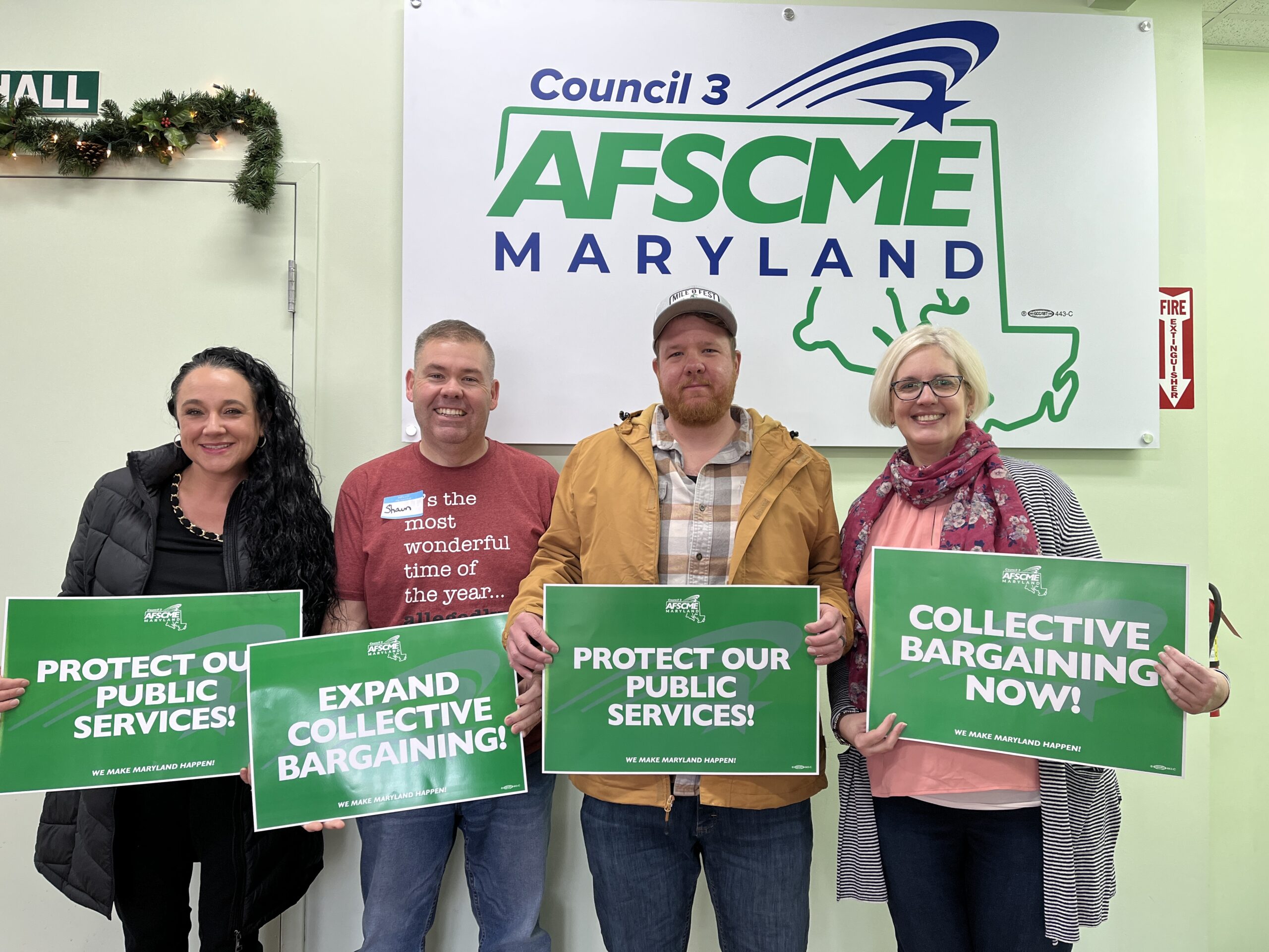 AFSCME supervisor members posing in front of an AFSCME Maryland sign each holding a sign that supports expanding collective bargaining rights to supervisors in Maryland